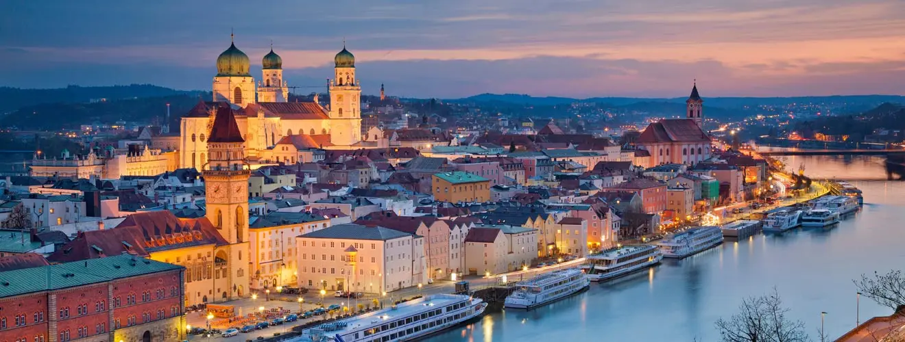 Passauer Altstadt mit Stephansdom und Flusskreuzfahrtschiffen an der Donau in der Abenddämmerung