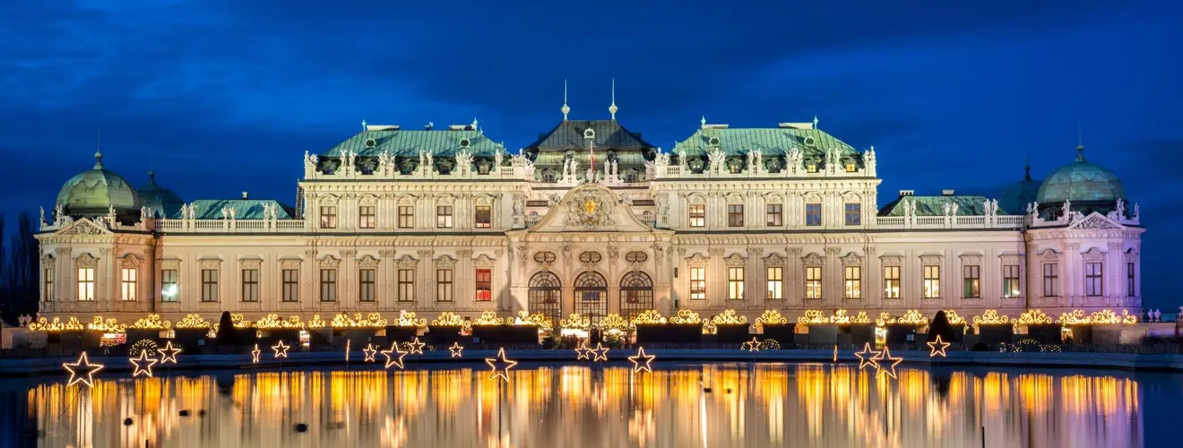 Beleuchtetes Schloss Belvedere in Wien mit Spiegelung im Wasser bei Nacht