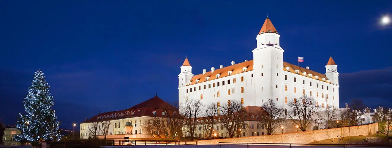 Beleuchtete Burg Bratislava mit geschmücktem Weihnachtsbaum bei Nacht