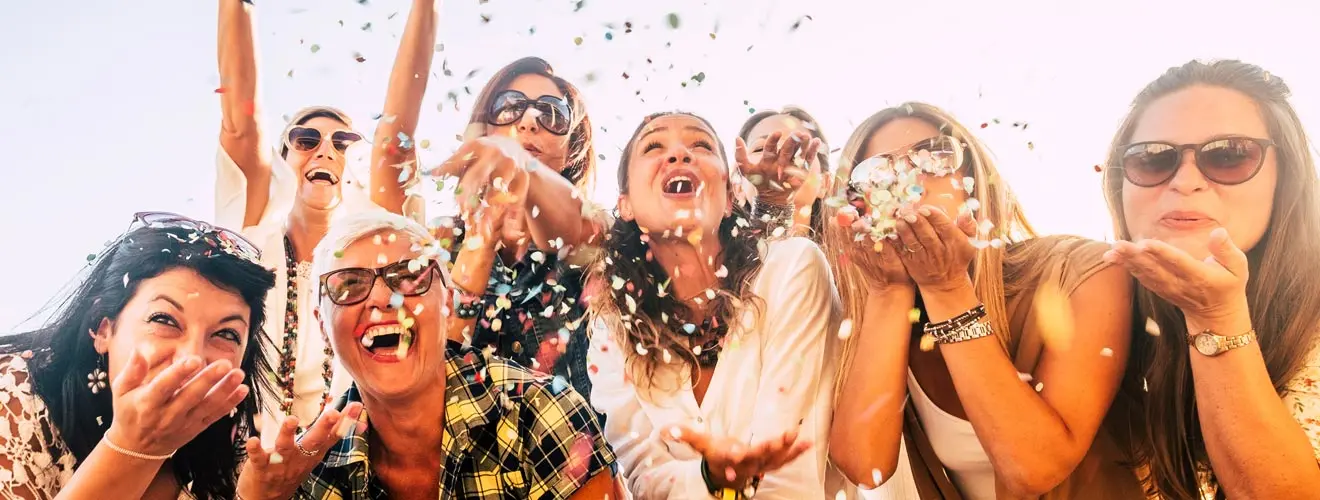 Frauen mit Sonnenbrillen feiern ausgelassen unter buntem Konfetti